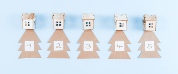 Advent calendar with craft trees, numbers and wooden houses on blue.