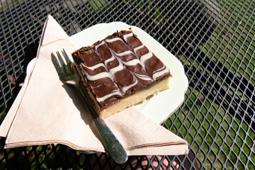 A slice of Millionaire's shortbread isloated on plate with fork. Also known as Caramel shortbread, caramel squares, caramel slice, chocolate caramel shortbread, and Wellington squares.