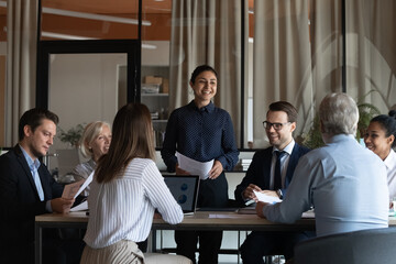 Business training. Young indian woman coach meet diverse corporate staff at conference room. Ethnic...