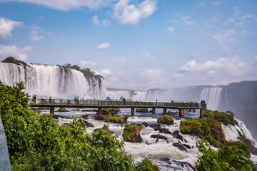 a waterfall in the middle of the forest with blue sky in the background.