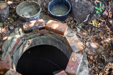 Fototapeta na wymiar Laying out of bricks the mouth of a septic well. Work with cement, construction of a septic tank