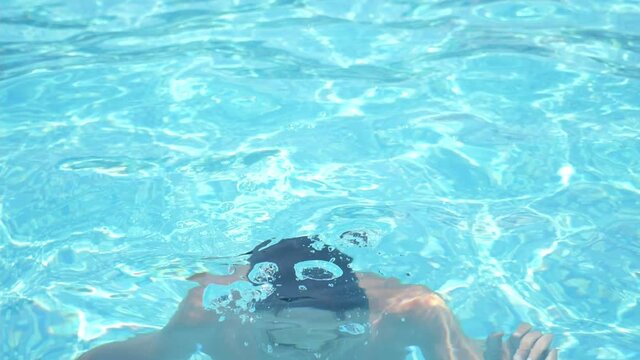 Entertaining guy sitting underwater in a wading pool on a sunny day in summer