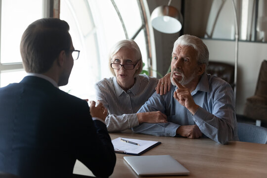 Dishonest Contractor. Angry Elderly Couple Sit At Broker Manager Office Demand Compensation For Breach Of Contract Bad Service. Annoyed Mature Spouses Scam Victims Complain Lawyer On Commercial Fraud