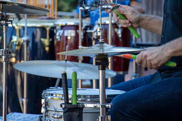 Close-up of dummer playing drum kit outdoors with multiple cymbals and snare. Side view of hands,...