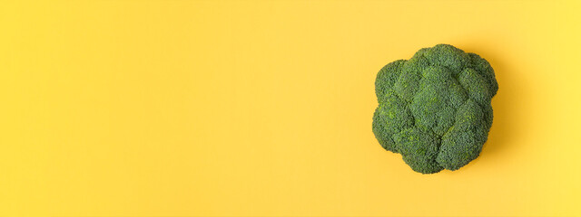 Top view fresh green broccoli vegetable on yellow. Extra banner Broccoli cabbage head on a colored background. Flat lay. Copy space. Healthy or vegetarian food concept
