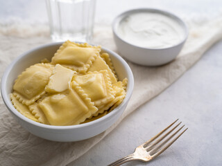 Italian ravioli and sour cream. Fork. White background. Minimalism. There are no people in the photo. Restaurant, hotel, café, home cooking, cooking blog, recipe book, home comfort.