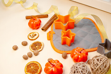 A composition of orange baking pans, oven mitt, pumpkins, dried oranges and cinnamon sticks.