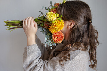 Naklejka premium Young woman with a bouquet of fresh chrysanthemums on a gray background.