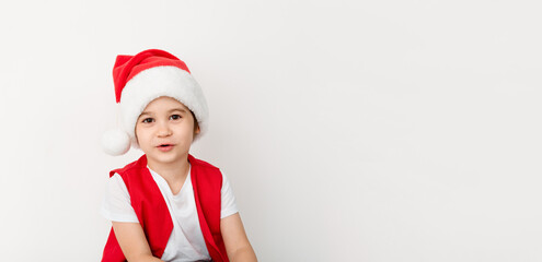 Portrait of beautiful happy child in red Santa Claus hat and costume isolated on a white background. Five-year little european boy. Banner. Copy space. Christmas time mockup design. New Year holiday