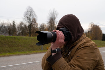 Close-up of a photographer shooting a city view in the cold autumn weather.