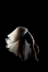 ballerina with a white dress and black top posing on black background. side lit silhouette. © Nikola Spasenoski