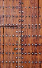Fototapeta premium Antique wooden gate with inlaid ironwork, from a large castle in Spain.