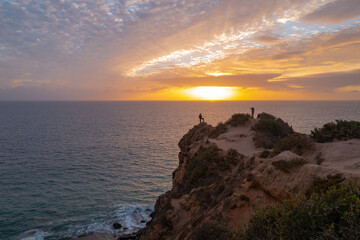 Dramatic scenic rock, seascape. Ocean sunset on sky background with colorful clouds. Calm sea with sunrise sky.