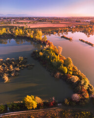 Aerial view of Casale sul Sile (Treviso province, Veneto region, Italy) countryside at sunrise in autumn. Lakes and foliage trees on front part