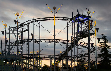 Beautiful landscape at sunset in which you can see a backlit roller coaster photographed from...