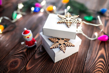 Two white gift boxes decorated with wooden snowflakes. Packing gifts for Christmas and New Year  with colorful garlands and lights. Wrapping stylish christmas gifts concept