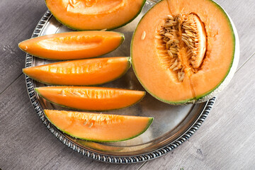 melon cantaloupe, half and slices on a silver platter top view