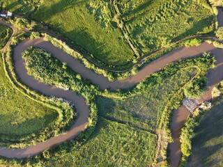 Streams meander in agricultural areas during the rainy season with plenty of water. Green and warm in the morning sunshine.