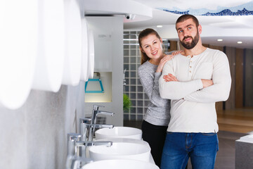 Positive couple choosing wash basin in bathroom furniture shop