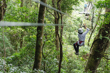 Naklejka na ściany i meble Joven adolescente colgando de cables para canopy en la selva de costa rica 