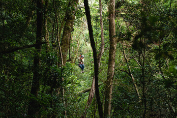Mujer latina colgando de cables de canopy en la selva de costa rica