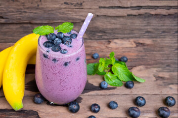 Blueberry mix banana smoothies purple colorful fruit juice milkshake blend beverage healthy high protein taste yummy drink in glass morning on wooden background.