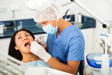 Female patient sitting in dental chair. Dentist is treating female patient