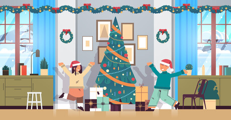 little children in santa hats happy to found gifts near fir tree new year christmas holidays celebration concept