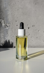 Naklejka premium Facial yellow oil serum glass bottle with pipette and shadow succulent shape, still life. Cosmetic beauty product for dry skin concept, vertical. Essence for skincare mockup, aromatherapy