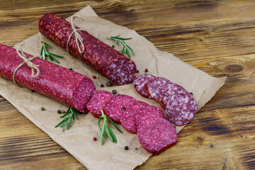 Salami sausages on craft paper on a wooden table