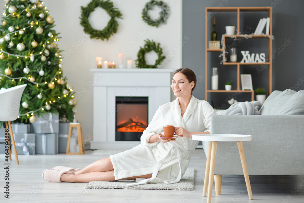 Sticker Beautiful young woman with cup of hot cacao drink at home on Christmas eve