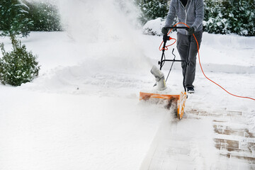 Man with machine removing snow in yard