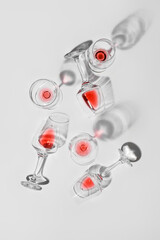 Stylish composition of glasses with leftover red wine on light background