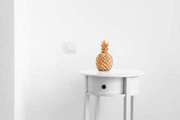 Table with decorative pineapple near white wall