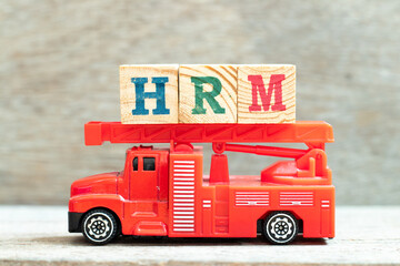 Fire ladder truck hold letter block in word HRM (Abbreviation of human resource management) on wood...