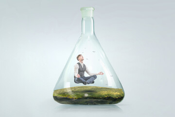 Business man doing yoga in lotus pose inside glass bottle