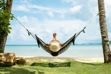 Happy woman in black bikini relaxing in hammock