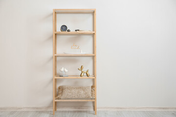 Stylish wooden shelf unit with decor near light wall