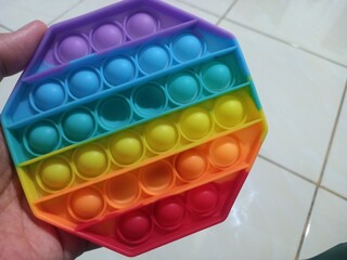 Man left hand showing pop it toy on home