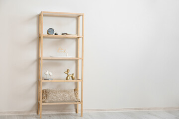 Stylish wooden shelf unit with decor near light wall