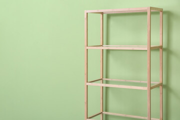 Stylish wooden shelf unit on green background, closeup