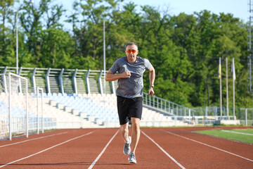 Obraz premium Sporty mature man jogging at stadium