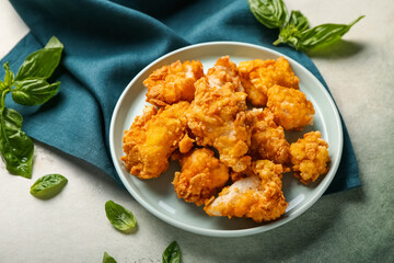 Plate with tasty fried popcorn chicken and basil on color background