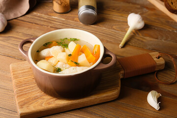 Board with bowl of tasty dumpling soup on wooden background