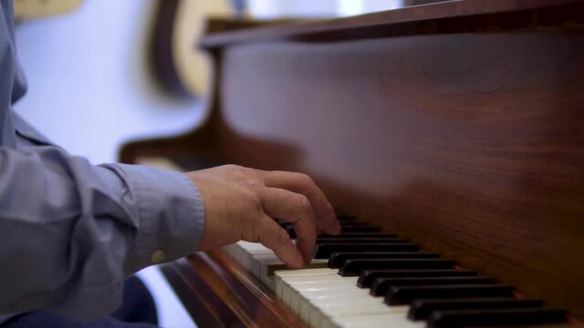 side view of a middle aged piano artist musician performing his song wearing blue shirt creative blurry backround slow motion