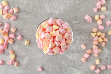 Glass with tasty marshmallows on grey background
