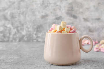 Cup with tasty marshmallows on grey background, closeup