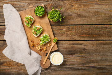 Board with tasty vegetarian bruschettas and sauce on wooden background
