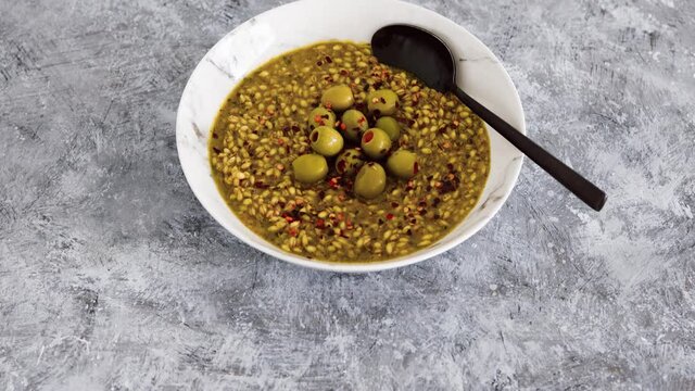 vegan spicy barley with olives and chilli flkes topping, healthy plant-based food