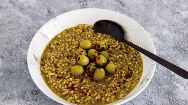 vegan spicy barley with olives and chilli flkes topping, healthy plant-based food